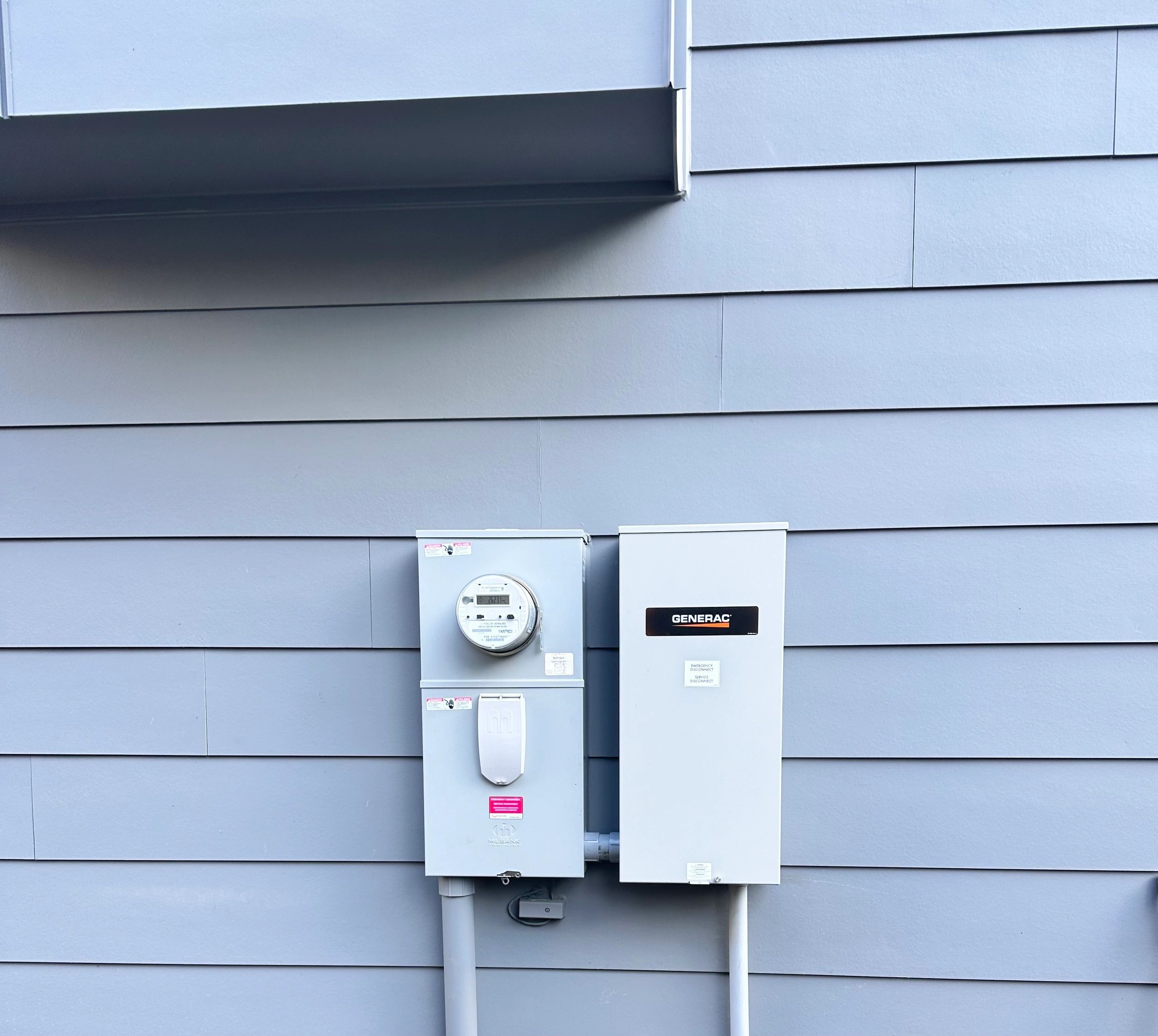 Utility meter and Generac automatic transfer switch installed on the siding of a home