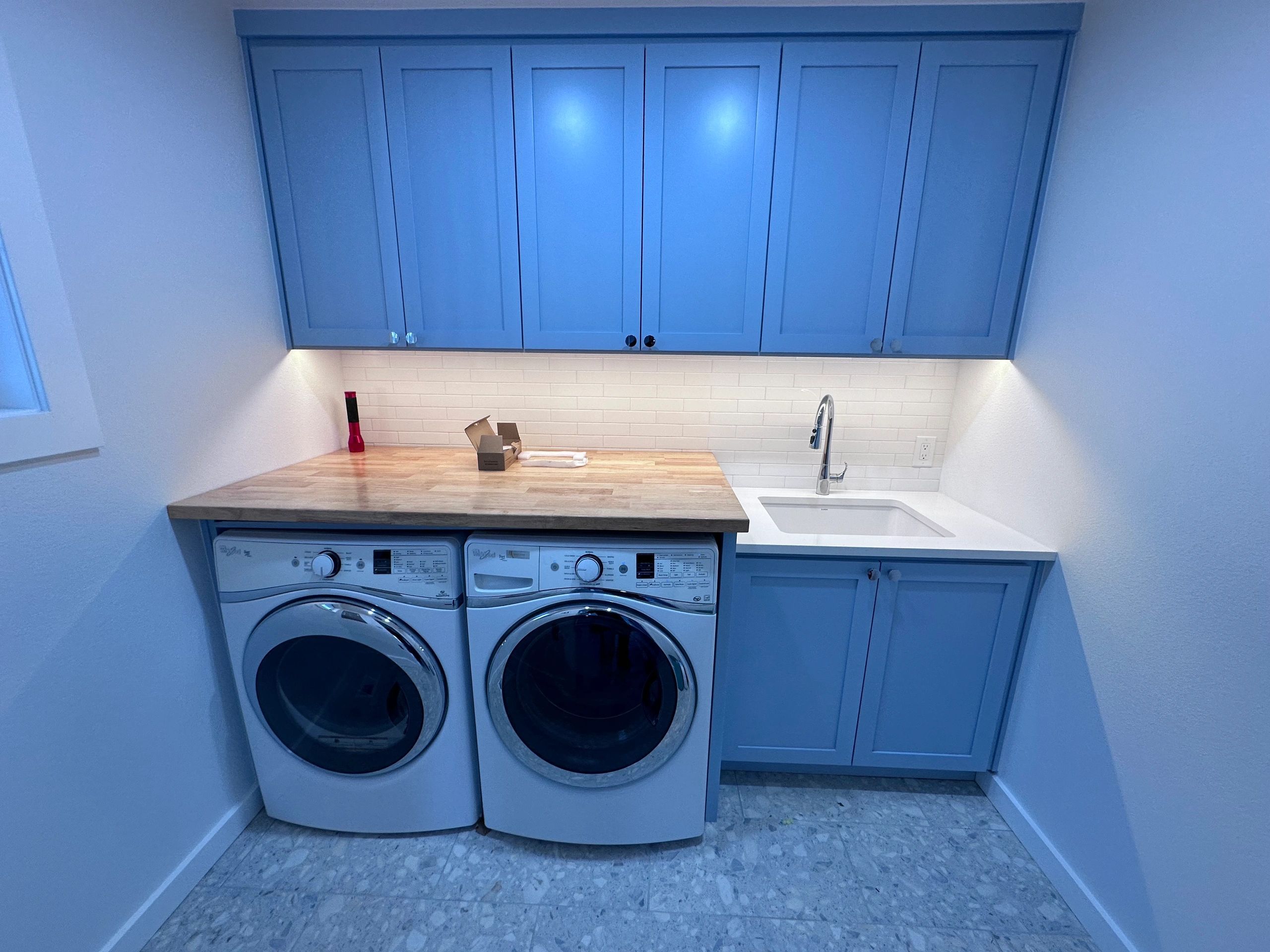 Laundry room with under-cabinet lighting above the washer and dryer