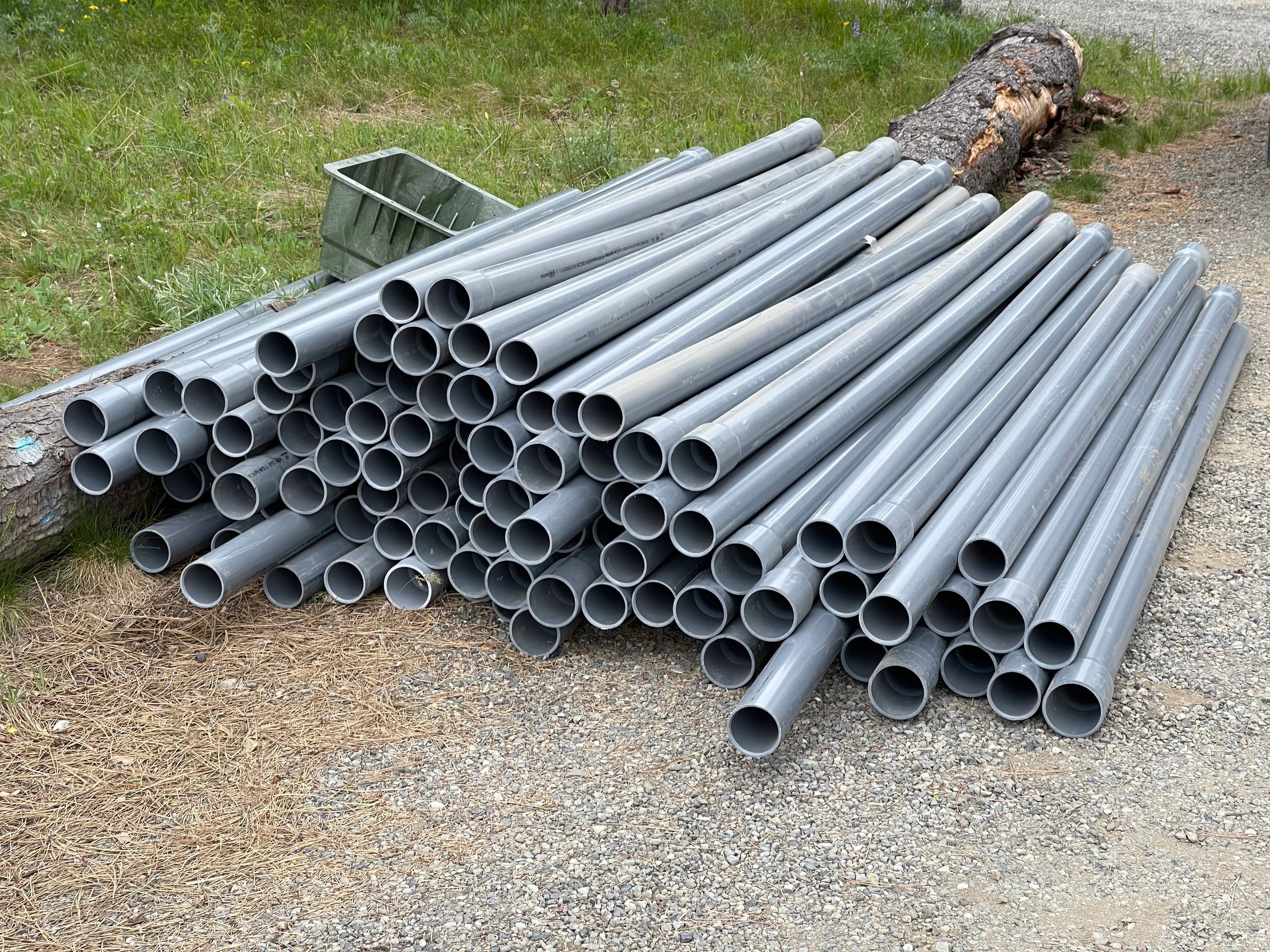 Stack of gray PVC electrical conduit staged on site for an underground installation