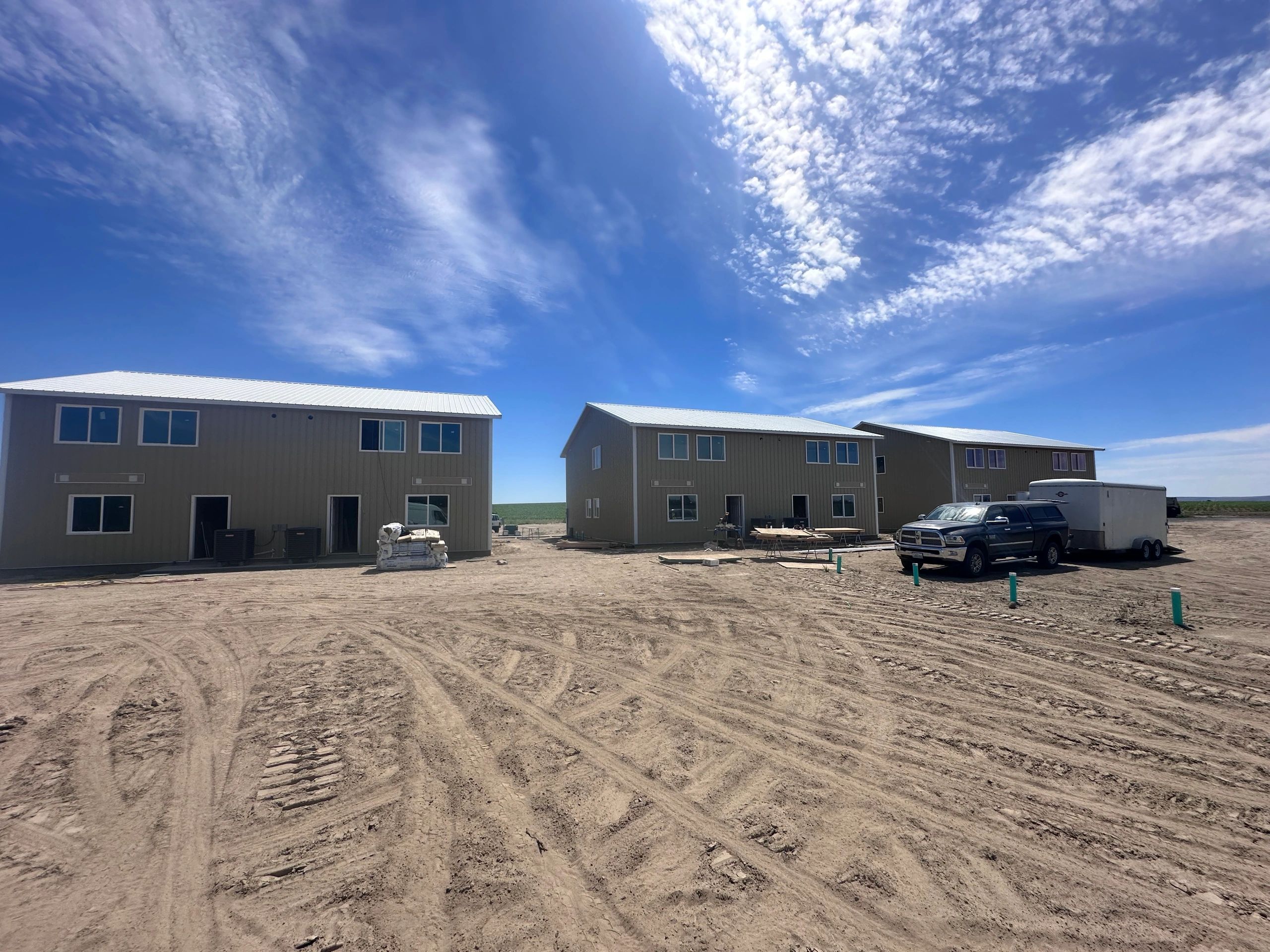 New two-story H-2A farmworker housing buildings under construction on an open agricultural site