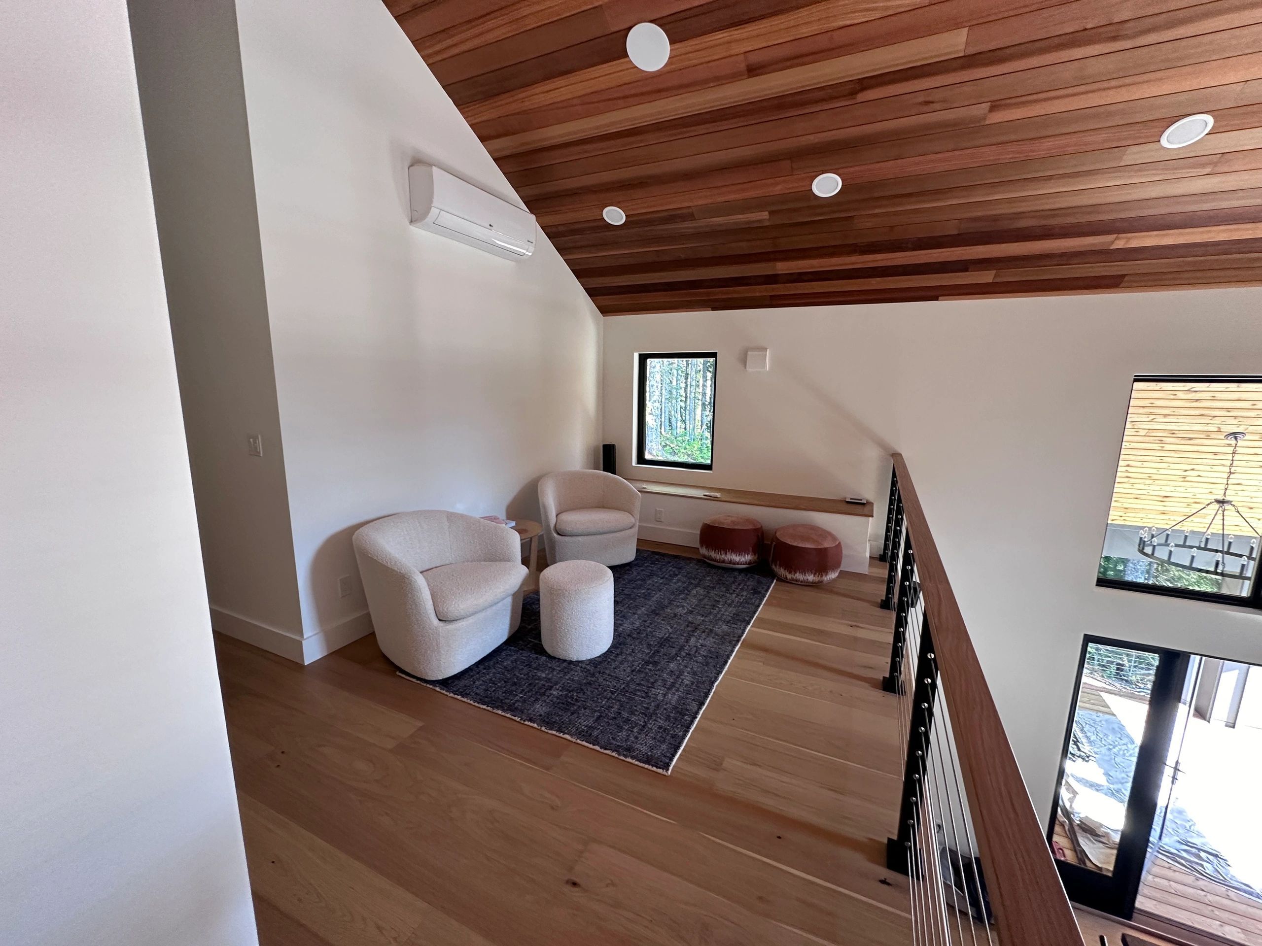 Finished loft with recessed lighting under a cedar ceiling and a ductless heat pump